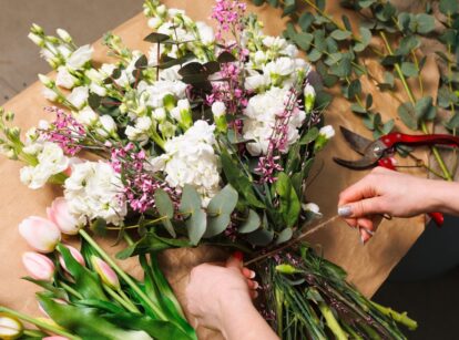 A florist arranges flowers into a wedding bouquet, carefully arranging blooms and greenery.