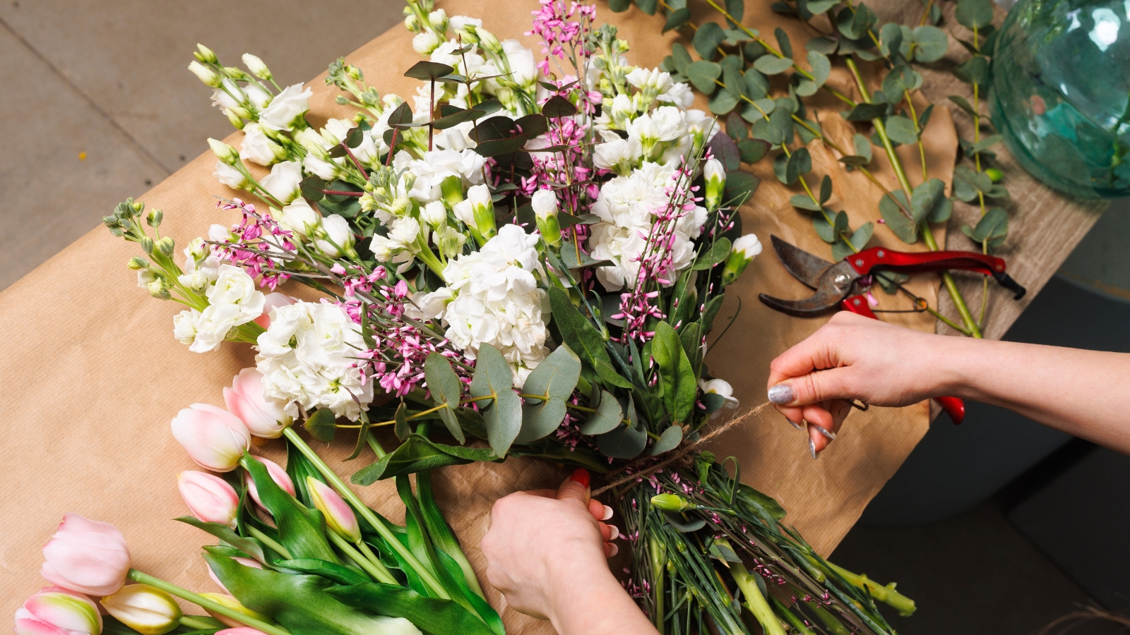 A florist arranges flowers into a wedding bouquet, carefully arranging blooms and greenery.