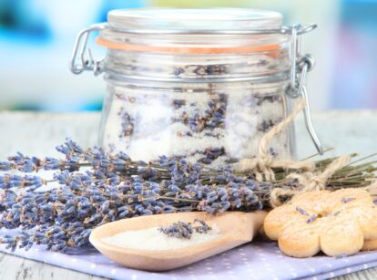 A jar of sugar infused with lavender, with fresh lavender flowers scattered nearby.