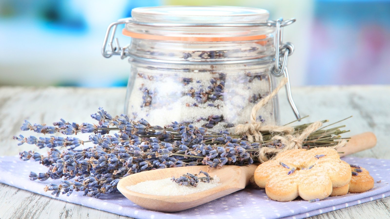 A jar of sugar infused with lavender, with fresh lavender flowers scattered nearby.