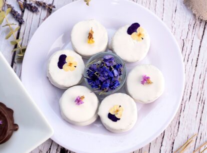 Flower candies made from real flowers in various colors arranged on a white plate.