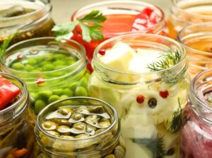 Close-up of various canned vegetables in jars with open lids, revealing their contents.